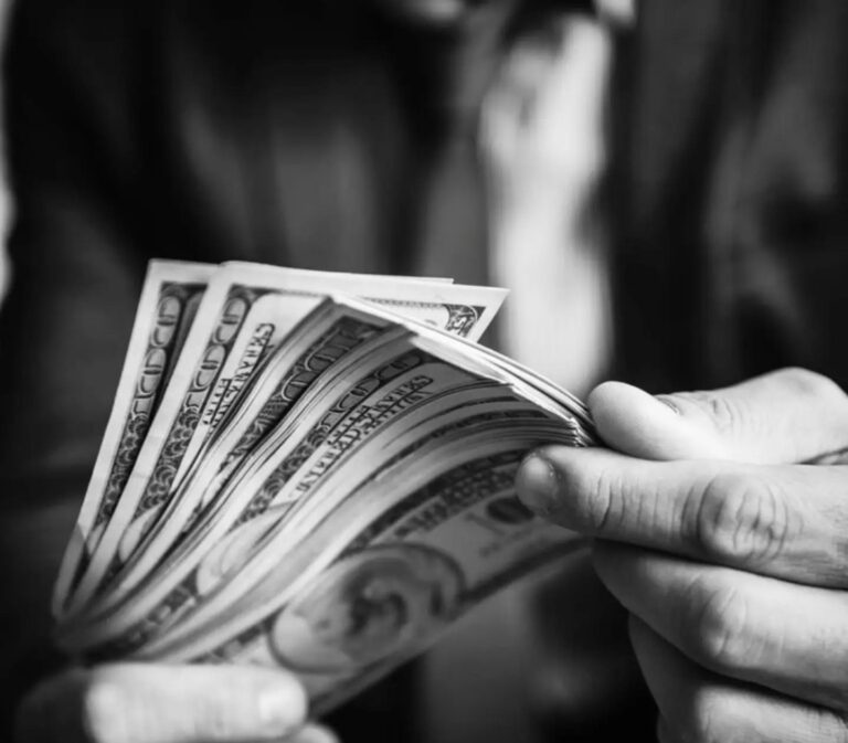 Manos contando billetes de cien dólares, en blanco y negro