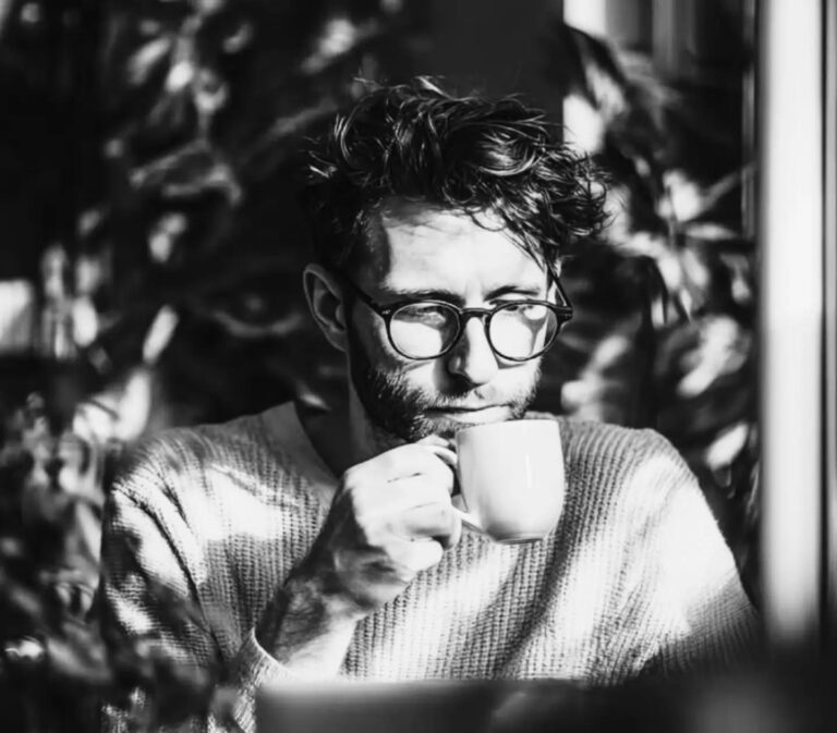 Persona revisando su computadora con una taza de café