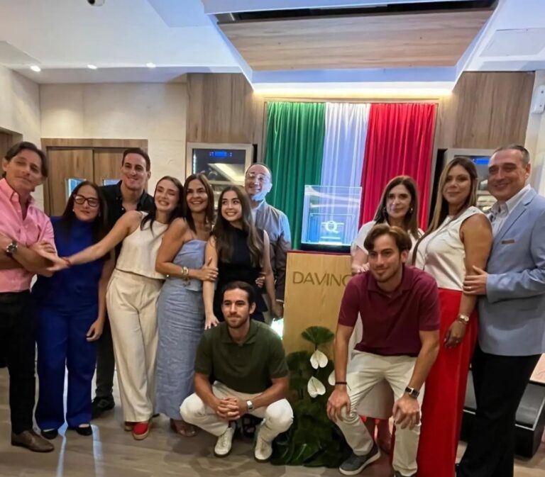 La familia Anaclerio posa frente a la bandera de Italia junto a la certificación Marchio Ospitalità Italiana