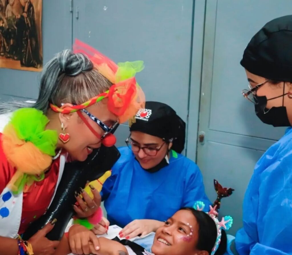 Niña atendida por odontólogos con un voluntario payaso en la jornada Cuidando Sonrisas