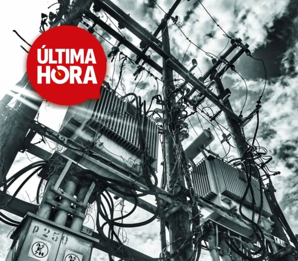 Poste con dos transformadores y cableado enredado, en blanco y negro